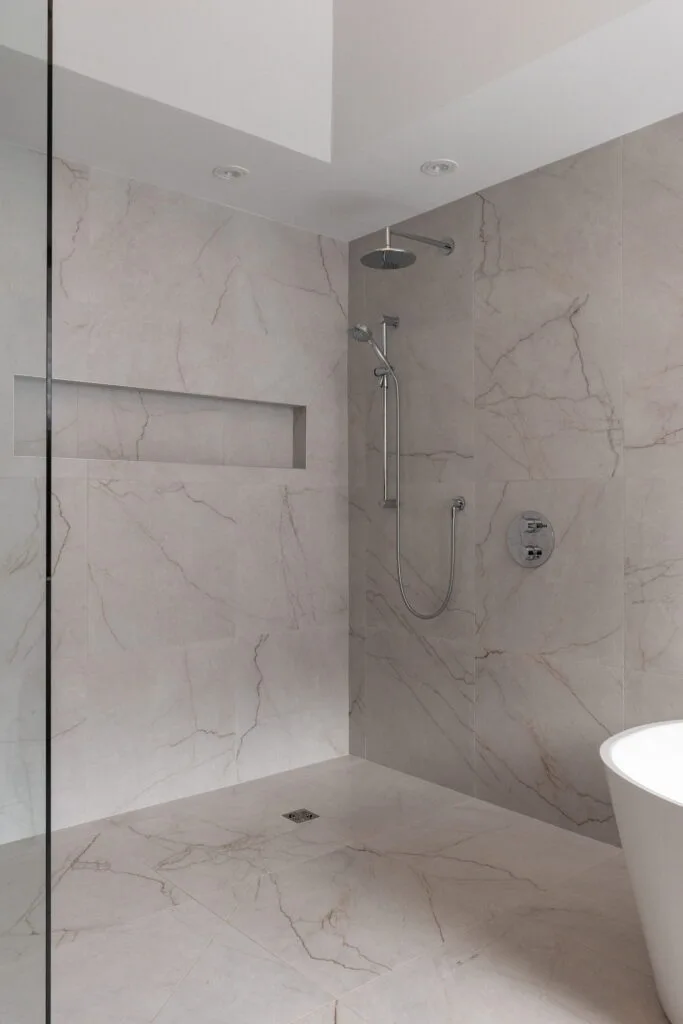 Luxury condominium walk-in shower featuring frameless glass enclosure, premium tile work, and modern high-end fixtures. The open, barrier-free design enhances accessibility while creating a sleek, spa-inspired atmosphere with refined finishes and a contemporary aesthetic.